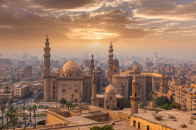 Islamic Cairo at sunset, featuring prominent historic landmarks.